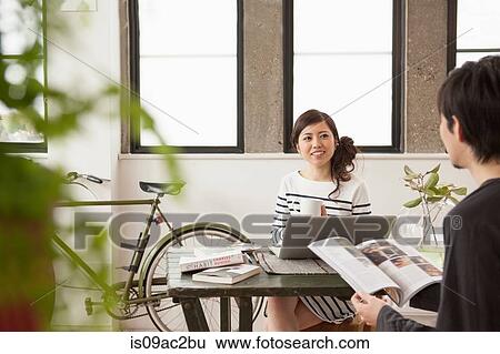 Young couple sitting at table with computer View Large Photo Image Stock Photograph - Young couple sitting at table with computer. Fotosearch