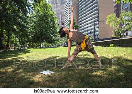 Stock Image - Young woman doing yoga in park. Fotosearch