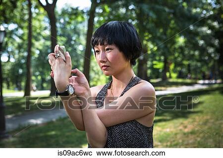 Young woman holding smartphone with arms twisted View Large Photo Image Stock Image - Young woman holding smartphone with arms twisted. Fotosearch