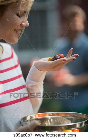 Stock Photo - Young woman holding tomatoes in hand. Fotosearch