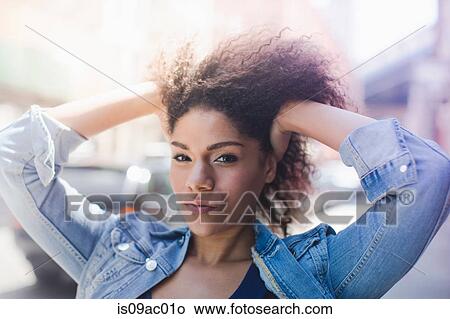 Picture - Young woman on street with hands in her hair. Fotosearch