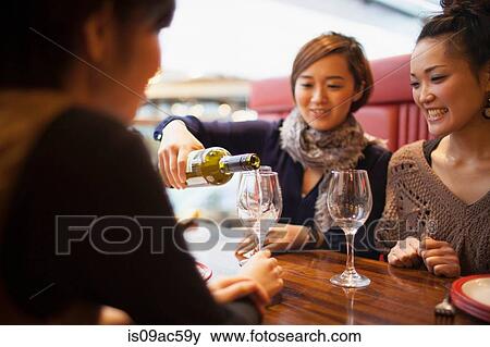 Stock Photo - Young woman pouring wine in restaurant. Fotosearch