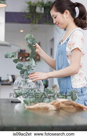 Stock Photograph - Young woman selecting foliage for vase arrangement. Fotosearch