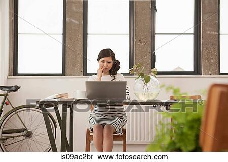 Young woman sitting at table with computer View Large Photo Image Stock Photography - Young woman sitting at table with computer. Fotosearch