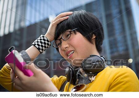 Picture - Young woman using mp3 player with hands in hair. Fotosearch