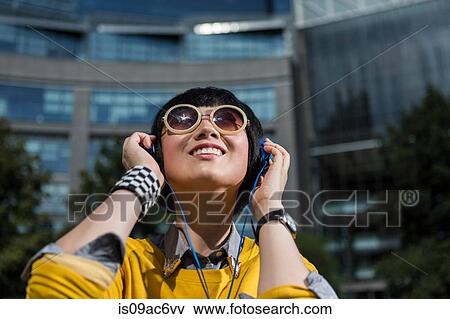 Young woman wearing sunglasses and headphones looking up View Large Photo Image Stock Photo - Young woman wearing sunglasses and headphones looking up. Fotosearch