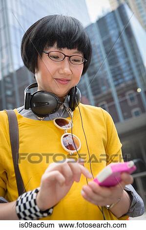 Picture - Young woman wearing yellow top using mp3 player. Fotosearch
