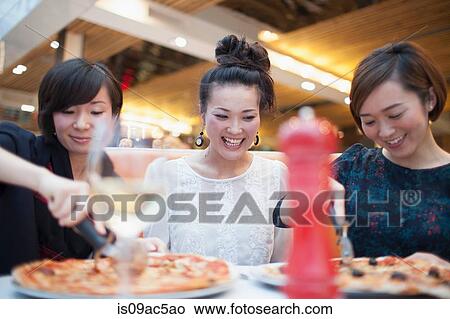 Young women eating pizza in restaurant View Large Photo Image Picture - Young women eating pizza in restaurant. Fotosearch