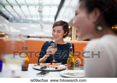 Stock Photo - Young women in restaurant eating pizza. Fotosearch