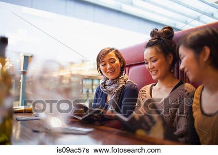Young women reading menus in cafe View Large Photo Image Stock Photograph - Young women reading menus in cafe. Fotosearch