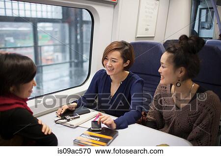 Young women talking on train View Large Photo Image Stock Image - Young women talking on train. Fotosearch