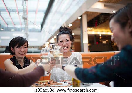 Young women toasting with wine in restaurant View Large Photo Image Stock Image - Young women toasting with wine in restaurant. Fotosearch