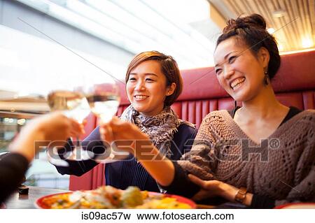 Young women toasting with wine in restaurant View Large Photo Image Stock Photo - Young women toasting with wine in restaurant. Fotosearch