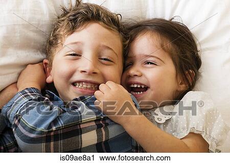 Stock Image - Children lying on bed. Fotosearch