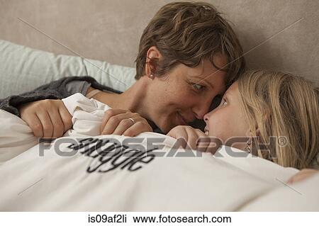 Close up portrait of mother and daughter snug in bed View Large Photo Image Stock Image - Close up portrait of mother and daughter snug in bed. Fotosearch