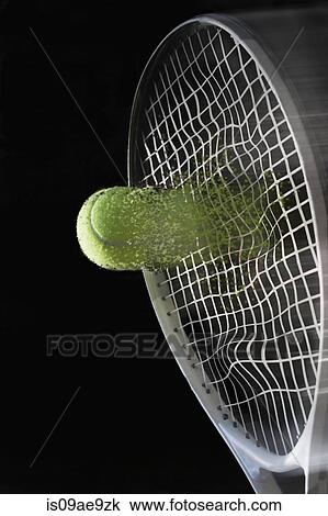 Stock Image - Close up tennis racket hitting ball with blurred motion. Fotosearch