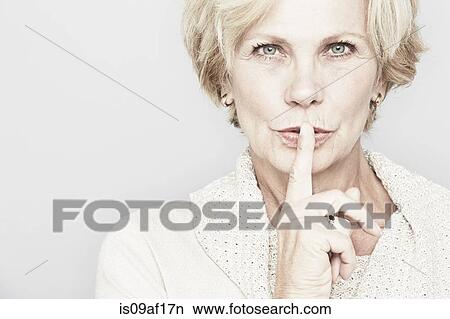 Picture - Cropped studio portrait of senior woman with finger on lips. Fotosearch