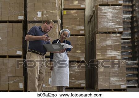 Factory worker and manager looking at clipboard in warehouse View Large Photo Image Picture - Factory worker and manager looking at clipboard in warehouse. Fotosearch