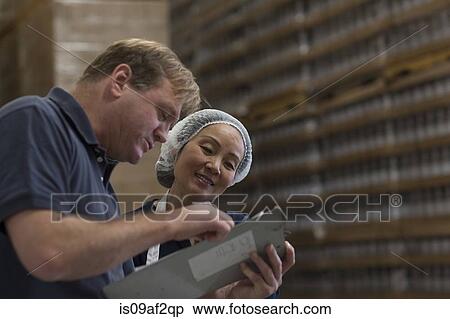 Stock Photography - Factory worker and manager looking at clipboard in warehouse. Fotosearch