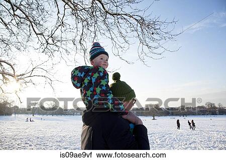Stock Image - Father carrying child on shoulder in park. Fotosearch