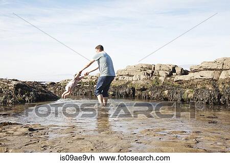 Stock Image - Father swinging child in pool. Fotosearch