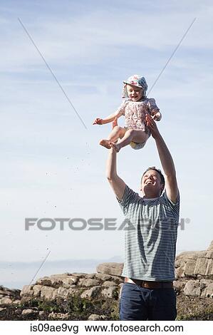 Stock Image - Father throwing child in air on beach. Fotosearch