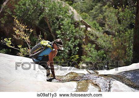 Stock Image - Female hiker crouching on rock, Mount Wilson, Red Rock Canyon, Nevada, USA. Fotosearch