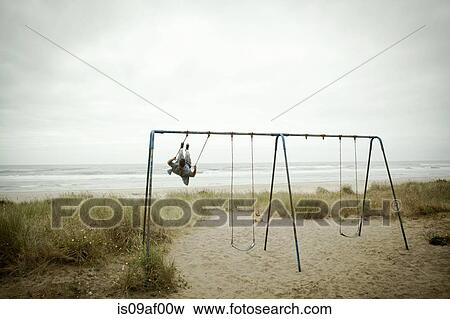 Female toddler watching father on beach swing View Large Photo Image Stock Photo - Female toddler watching father on beach swing. Fotosearch