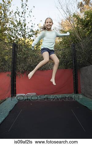 Stock Photograph - Girl having fun on garden trampoline. Fotosearch