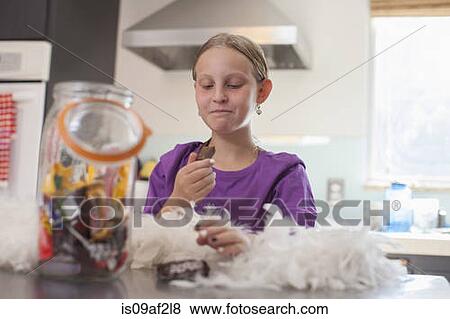 Girl secretly enjoying biscuit from biscuit barrel View Large Photo Image Stock Photo - Girl secretly enjoying biscuit from biscuit barrel. Fotosearch