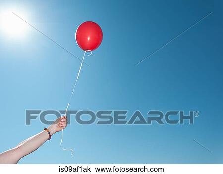 Hand holding single red balloon against blue sky View Large Photo Image Stock Image - Hand holding single red balloon against blue sky. Fotosearch