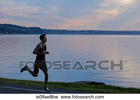 Jogger running past lake View Large Photo Image Stock Photo - Jogger running past lake. Fotosearch
