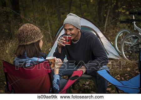 Mature couple sitting on camping chairs outside tent, drinking hot drinks View Large Photo Image Stock Image - Mature couple sitting on camping chairs outside tent, drinking hot drinks. Fotosearch