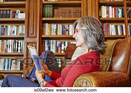Mature woman sitting in home study using digital tablet View Large Photo Image Stock Image - Mature woman sitting in home study using digital tablet. Fotosearch