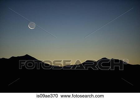 Stock Image - Moon and mountains in silhouette, Moab, Utah, USA. Fotosearch