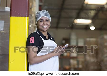 Stock Image - Portrait of female factory worker using cell phone. Fotosearch