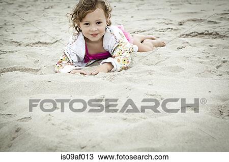 Portrait of female toddler lying in sand View Large Photo Image Stock Image - Portrait of female toddler lying in sand. Fotosearch