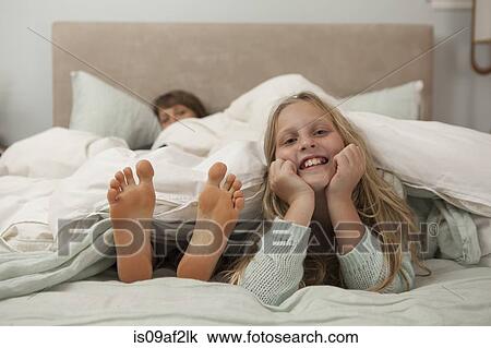 Portrait of girl lying on bed with mothers feet View Large Photo Image Stock Image - Portrait of girl lying on bed with mothers feet. Fotosearch