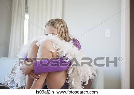 Stock Image - Portrait of girl sitting hugging knees and hiding face. Fotosearch