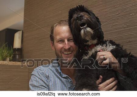Stock Photography - Portrait of mature man holding up pet dog. Fotosearch
