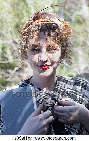 Stock Photography - Portrait of young woman holding book in park. Fotosearch