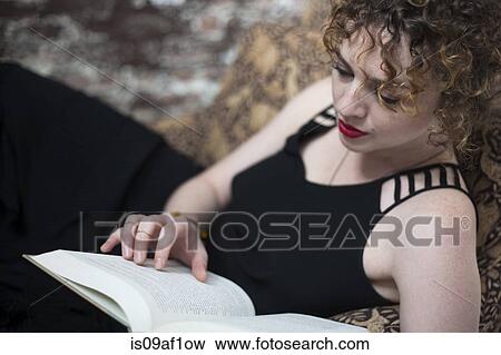 Portrait of young woman reclining and reading book View Large Photo Image Stock Photo - Portrait of young woman reclining and reading book. Fotosearch