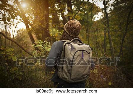 Rear view of woman walking through forest, carrying rucksack View Large Photo Image Stock Image - Rear view of woman walking through forest, carrying rucksack. Fotosearch