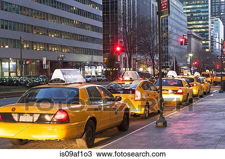 Stock Image - Row of yellow cabs next to sidewalk, New York, USA. Fotosearch