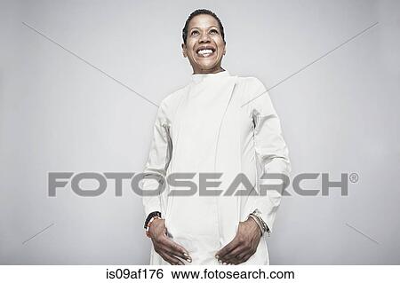 Stock Photograph - Studio portrait of mature woman with hand in pockets. Fotosearch