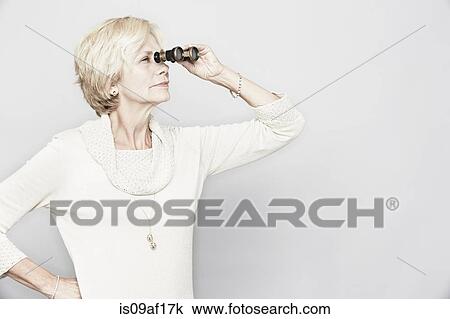 Studio portrait of senior woman looking through binoculars View Large Photo Image Stock Image - Studio portrait of senior woman looking through binoculars. Fotosearch