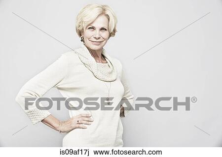 Stock Image - Studio portrait of senior woman with hands on hips. Fotosearch