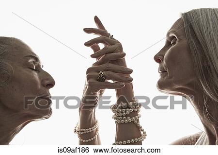 Stock Photograph - Studio shot of two mature women in profile with eyes closed. Fotosearch