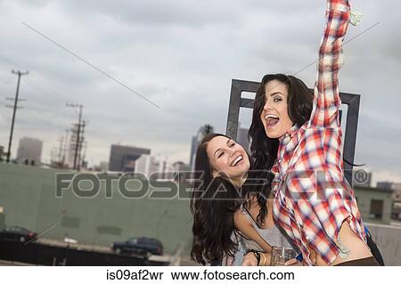 Two female friends jumping around at rooftop party View Large Photo Image Stock Photography - Two female friends jumping around at rooftop party. Fotosearch