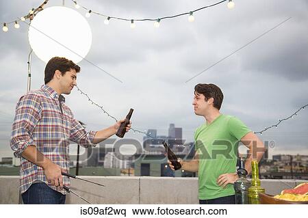 Two male adult friends chatting at rooftop barbecue View Large Photo Image Stock Photography - Two male adult friends chatting at rooftop barbecue. Fotosearch